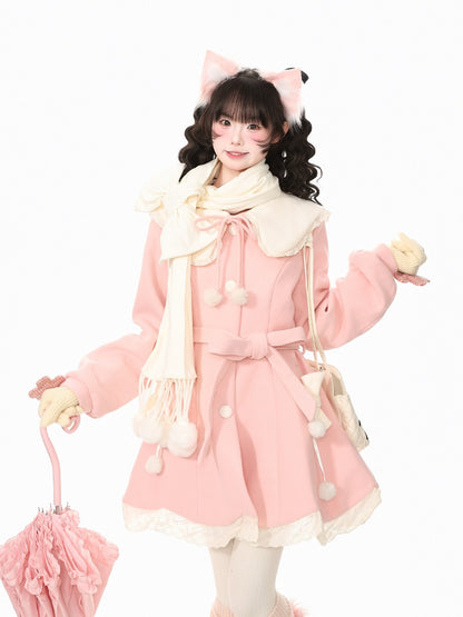 A young woman modeling a cute pink and cream Lolita-style winter outfit, featuring a pink coat with cream trim, a matching cream scarf, cream gloves, and a pink cat-ear headband, holding a pink umbrella against a plain white background.