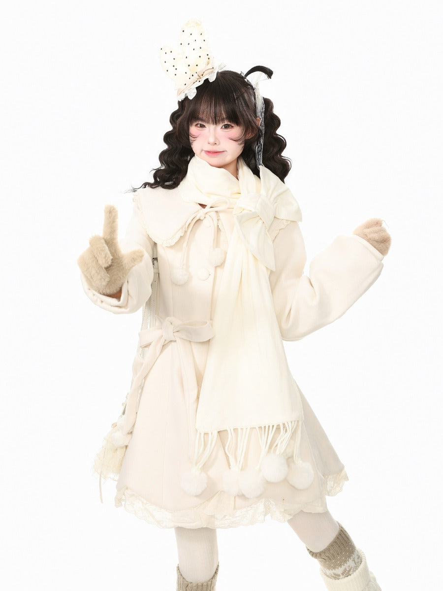 A young girl modeling a cream-colored winter outfit consisting of a long coat with a large bow, a matching scarf, gloves, and socks, along with a decorative headband, set against a plain white background.
