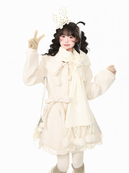A young girl with dark curly hair wearing a cream-colored winter outfit, including a long-sleeve coat, matching scarf, gloves, and a decorative headband, posing against a solid white background.