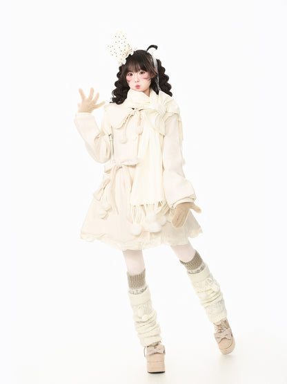 A model posing in a cream-colored Lolita-style outfit featuring a ruffled long-sleeve dress, matching scarf, beige knit leg warmers, and platform shoes against a solid white background.
