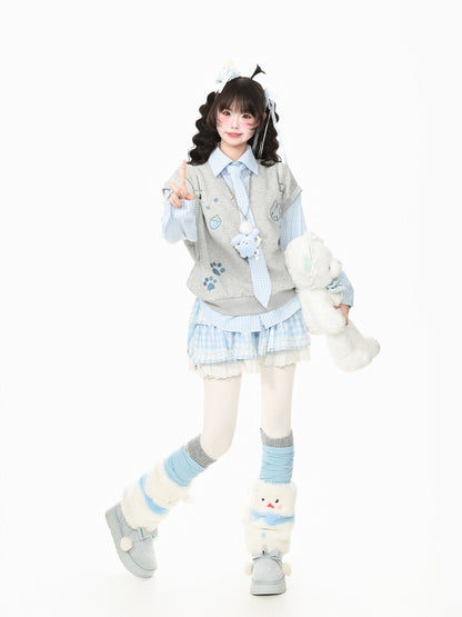 A young girl models a cute, pastel-themed outfit consisting of a light blue and white plaid mini skirt, a gray vest with blue paw prints, a striped shirt, and matching accessories, while holding a white plush toy against a solid white background.