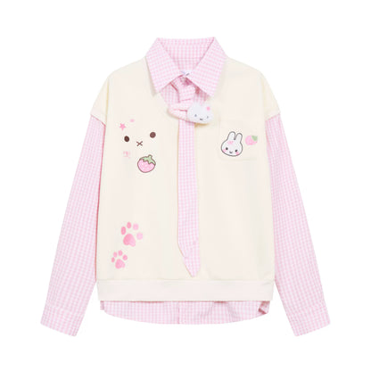 A pastel pink and cream long-sleeve collared shirt jacket with cute cartoon bunny and strawberry graphics, pink paw prints, and a matching pink gingham pattern on the sleeves and collar.