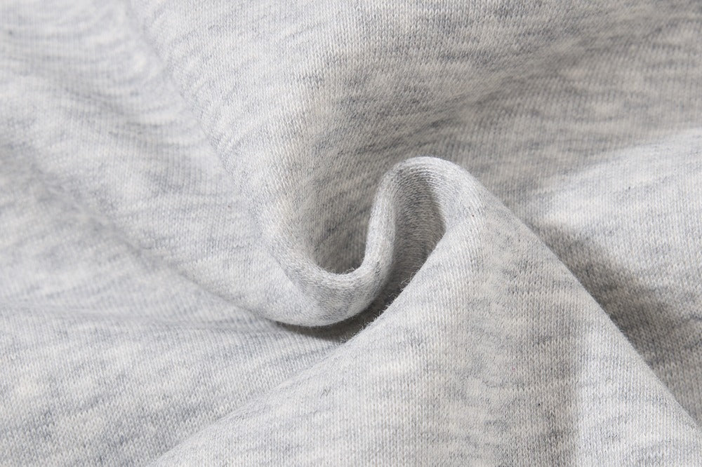 Close-up of light heather gray knit fabric with soft folds and a textured weave.