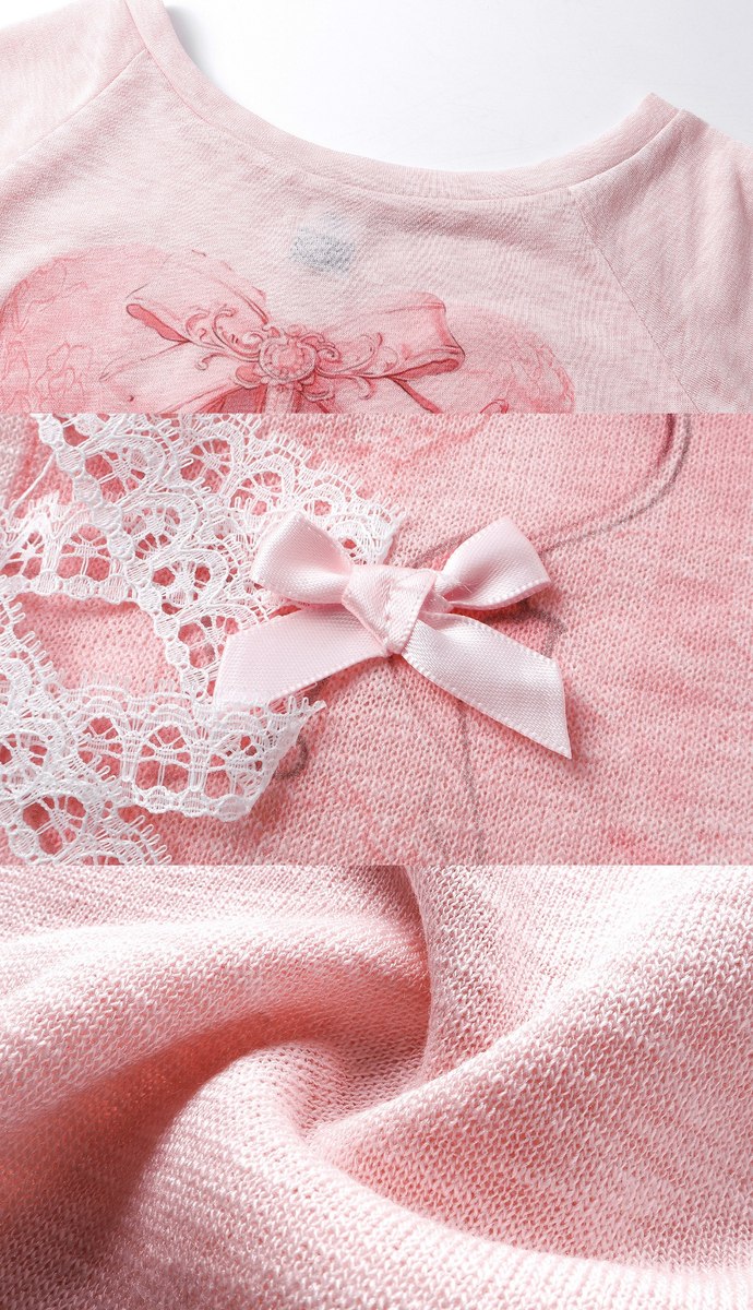 Close-up of a light pink knit garment with a matching pink satin bow, white lace trim, and a subtle heart motif on the chest.