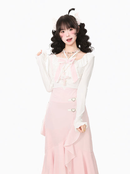 A young woman modeling a cute, two-piece pastel outfit consisting of a white long-sleeve top with a pink bow and a matching pink skirt with decorative buttons, set against a plain white background.