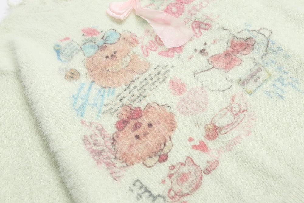 A close-up of a soft, pale pink plush blanket featuring cute teddy bear illustrations in pink, blue, and white, with a matching pink bow at the top.