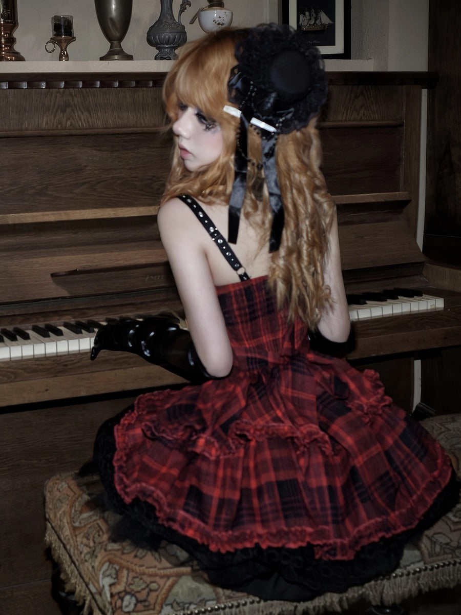A woman with long wavy orange-blonde hair sits on a patterned bench in front of a wooden piano, wearing a red and black plaid strapless dress with black lace-up shoulder straps, black gloves, and a black hat with ribbons.