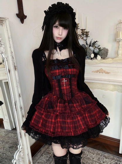 A person wearing a red and black plaid Lolita-style dress with a black corset-style bodice, long black sleeves, ruffled skirt, lace hem, black thigh-high stockings, and a black floral headpiece, standing indoors in front of a mirror and fireplace mantel.