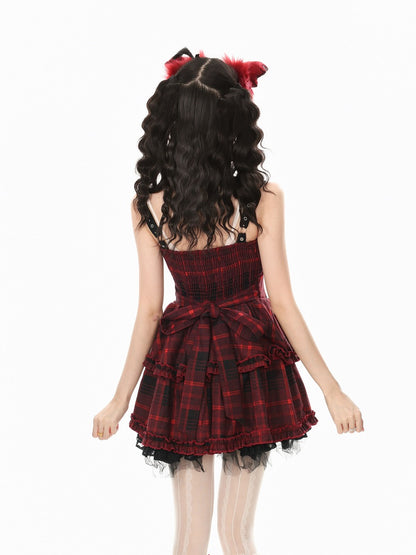 A girl shown from the back wearing a red and black plaid strapless dress with a ruffled tiered skirt and a matching red and black plaid hair accessory with fluffy red ends, against a plain white background.