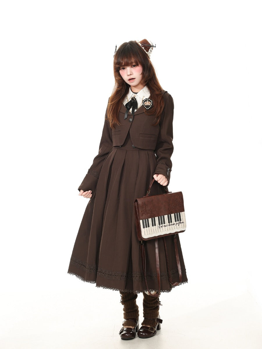 A model wearing a dark brown Victorian-style Lolita dress with a pleated skirt, matching cropped jacket, white collar, and a black bow. She is holding a brown piano-themed handbag and wearing brown knee-high boots against a solid white background.