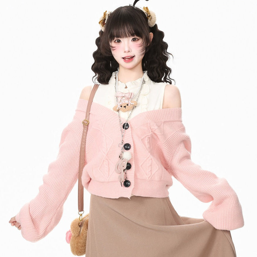 A young woman modeling a light pink off-the-shoulder knit cardigan with black buttons, worn over a white top and paired with a beige maxi skirt. She is accessorized with a small teddy bear shoulder bag and a decorative headband, set against a plain white studio background.