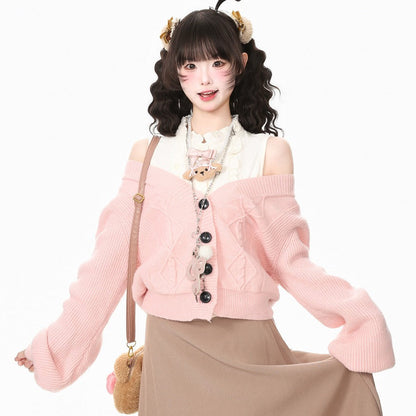 A young woman modeling a light pink off-the-shoulder knit cardigan with black buttons, worn over a white top and paired with a beige maxi skirt. She is accessorized with a small teddy bear shoulder bag and a decorative headband, set against a plain white studio background.