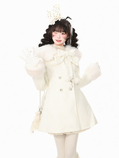 A young girl modeling a cream-colored double-breasted coat with a large faux-fur collar, matching gloves, and a decorative bunny head headband, set against a plain white background.