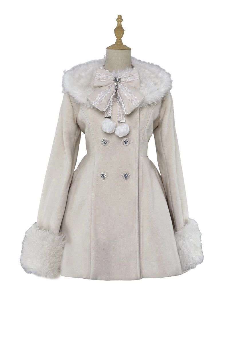 A cream-colored double-breasted coat with faux fur trim on the collar and cuffs, featuring a large decorative bow at the neck and silver-tone buttons, displayed on a mannequin against a white background.