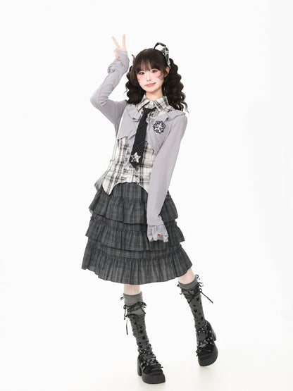 A model posing in a schoolgirl-style outfit featuring a gray long-sleeve cardigan, a black and white plaid shirt, a black tie, a pleated gray skirt, and black lace-up boots, set against a plain white background.