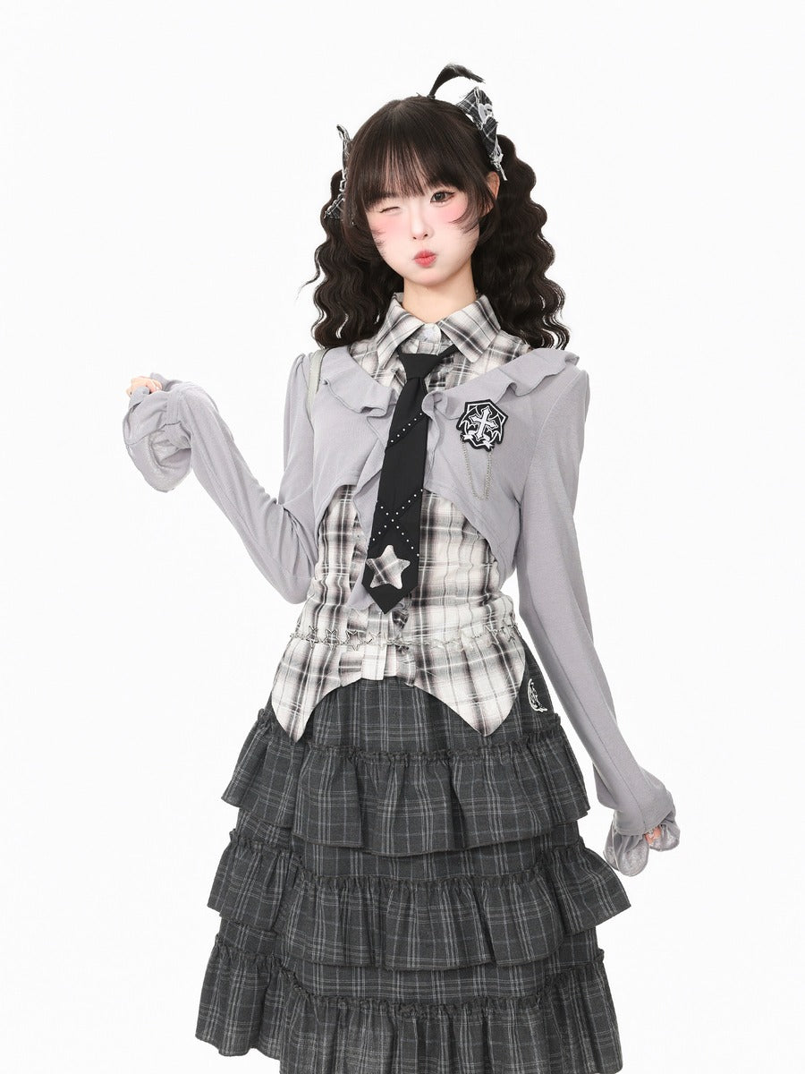 A young woman modeling a gothic Lolita-style outfit consisting of a gray long-sleeve cardigan, a black and white plaid vest, a black star-patterned tie, and a dark gray tiered plaid skirt, set against a plain white background.