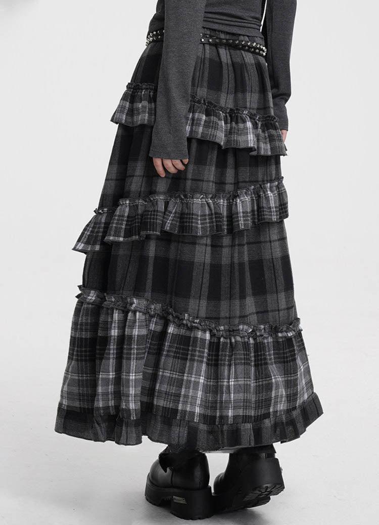 A black and gray plaid tiered maxi skirt with ruffled layers, styled with a dark gray long-sleeve top and black platform boots against a plain white studio background.