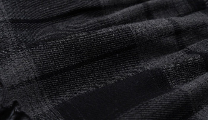 Close-up of a dark charcoal gray and black plaid fabric texture with a woven pattern.