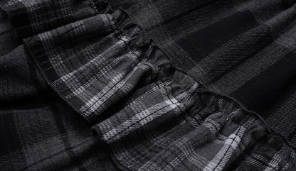 Close-up of a black and gray plaid fabric with gathered ruffles, showing the texture and pattern details.