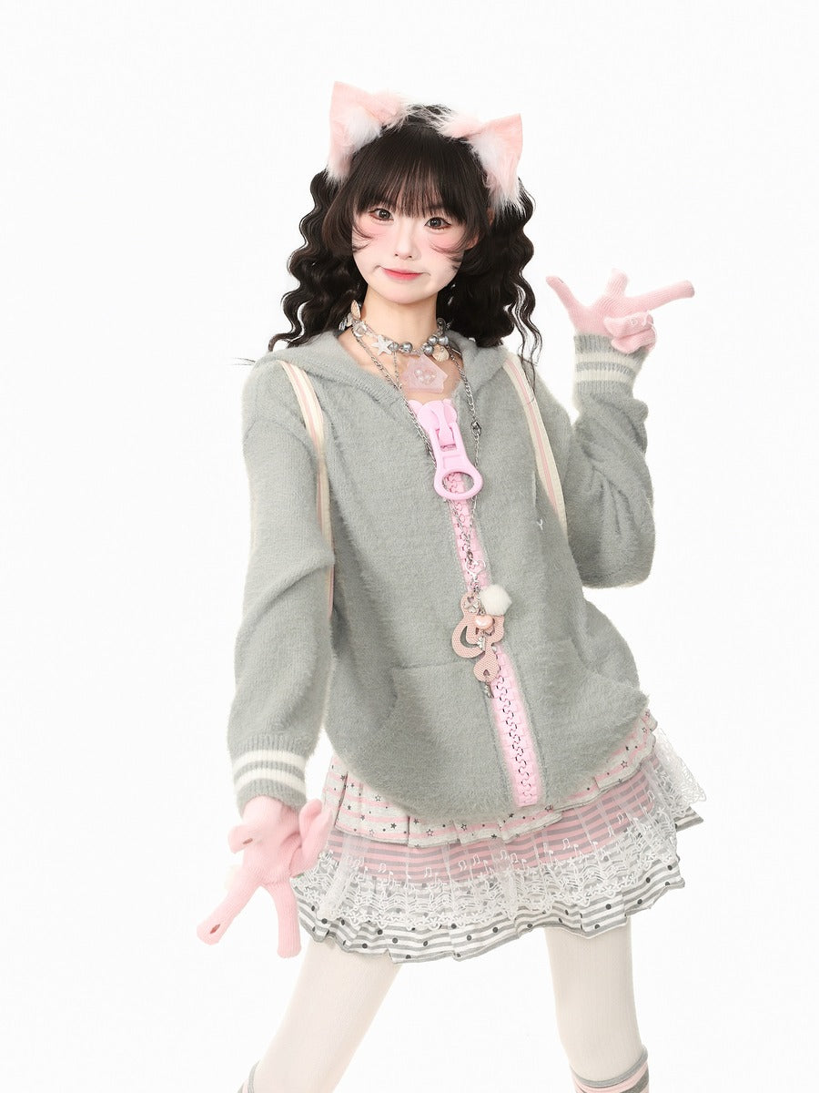 A young woman modeling a gray and pink cat-themed outfit with a zip-up hoodie, pleated skirt, and accessories, posing against a solid white background.