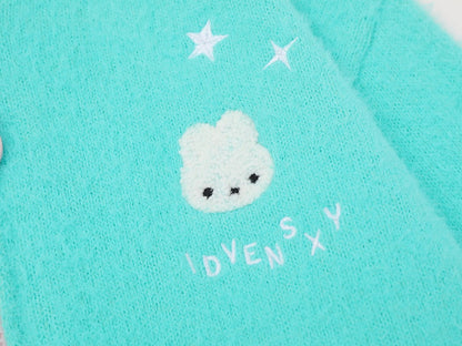 Close-up of a turquoise knit fabric featuring a white embroidered bunny face with black eyes, two white stars above, and the text 'IDVENSXY' in white below.