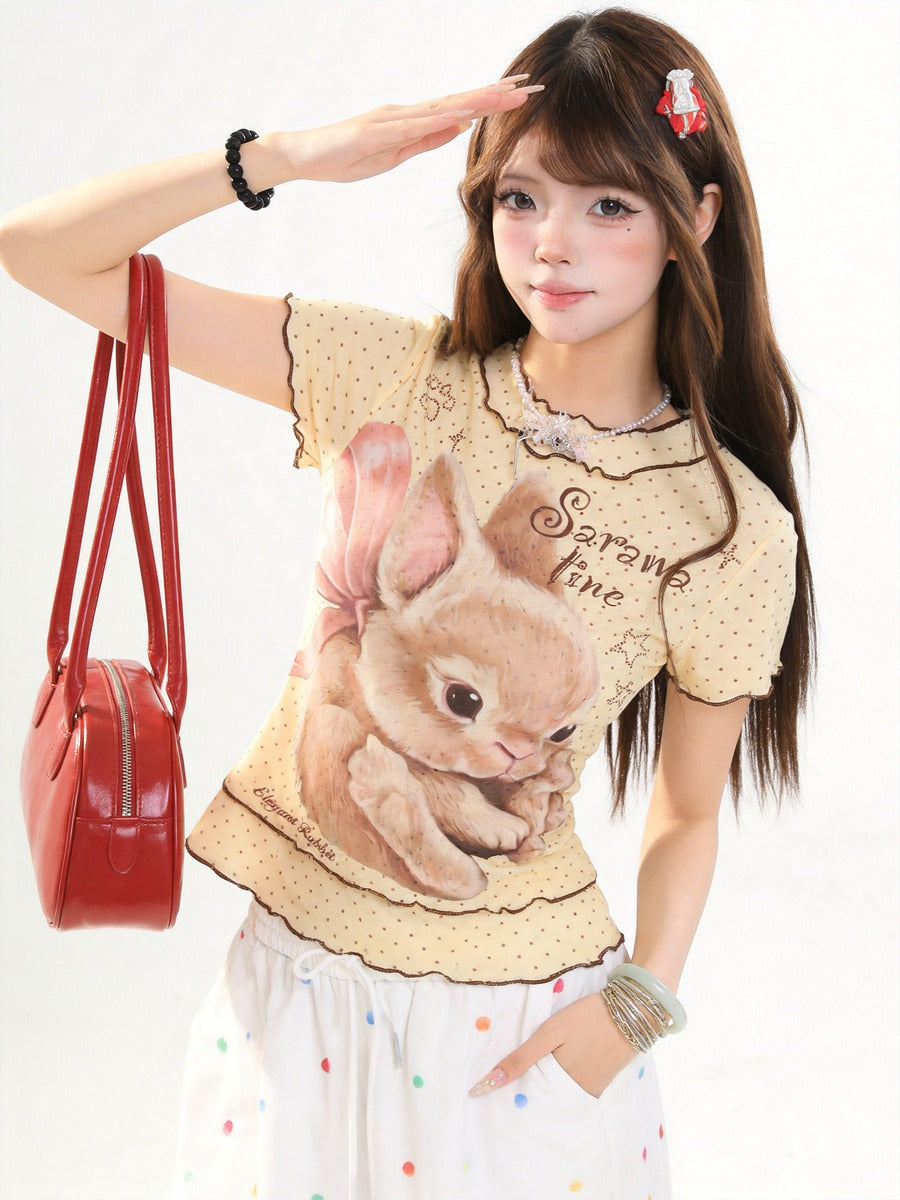 Woman wearing a shirt with a bunny design and holding a red handbag.