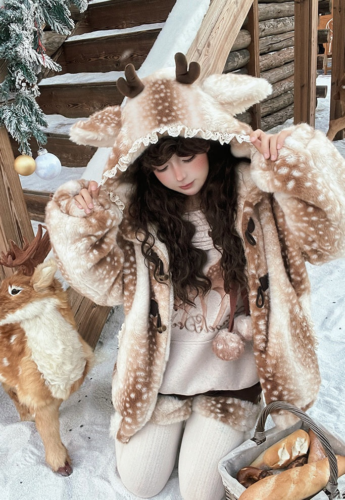 Person wearing a deer-themed hoodie in a snowy setting with a small deer and Christmas decorations.