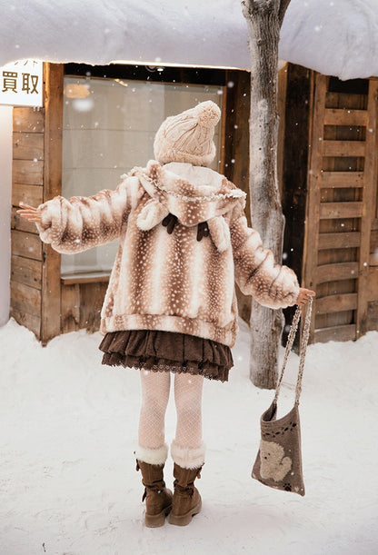 A girl in a cute lolita style deer winter coat and boots standing in the snow near wooden structures.