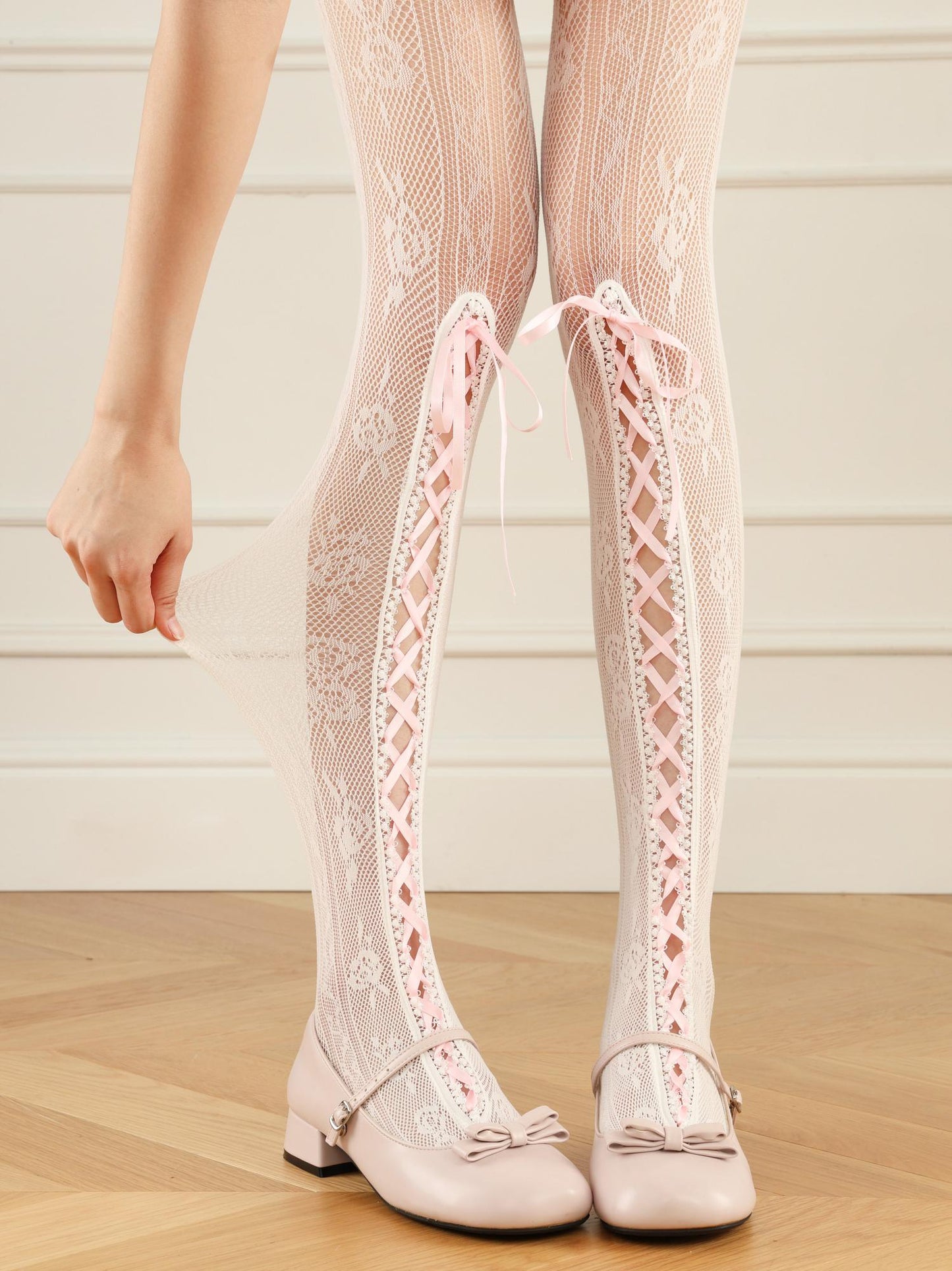 White lace knee-high stockings with matching shoes on a wooden floor.