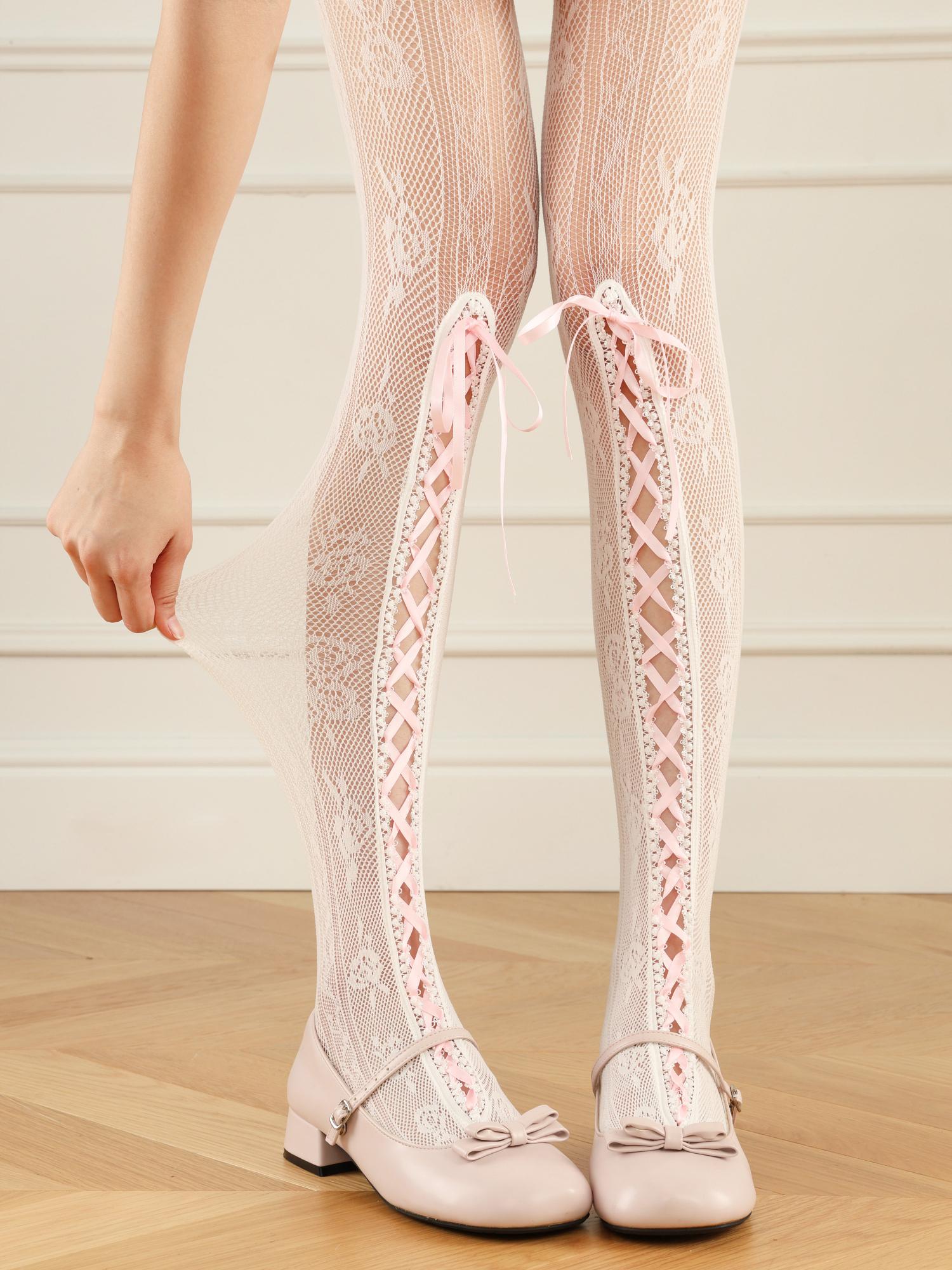 White lace knee-high stockings with matching shoes on a wooden floor.
