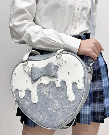 Heart-shaped bag with a bow design held by a person wearing a white shirt and plaid skirt.