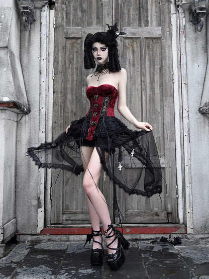 Woman in a gothic outfit with a red corset and black skirt standing in front of a wooden door.