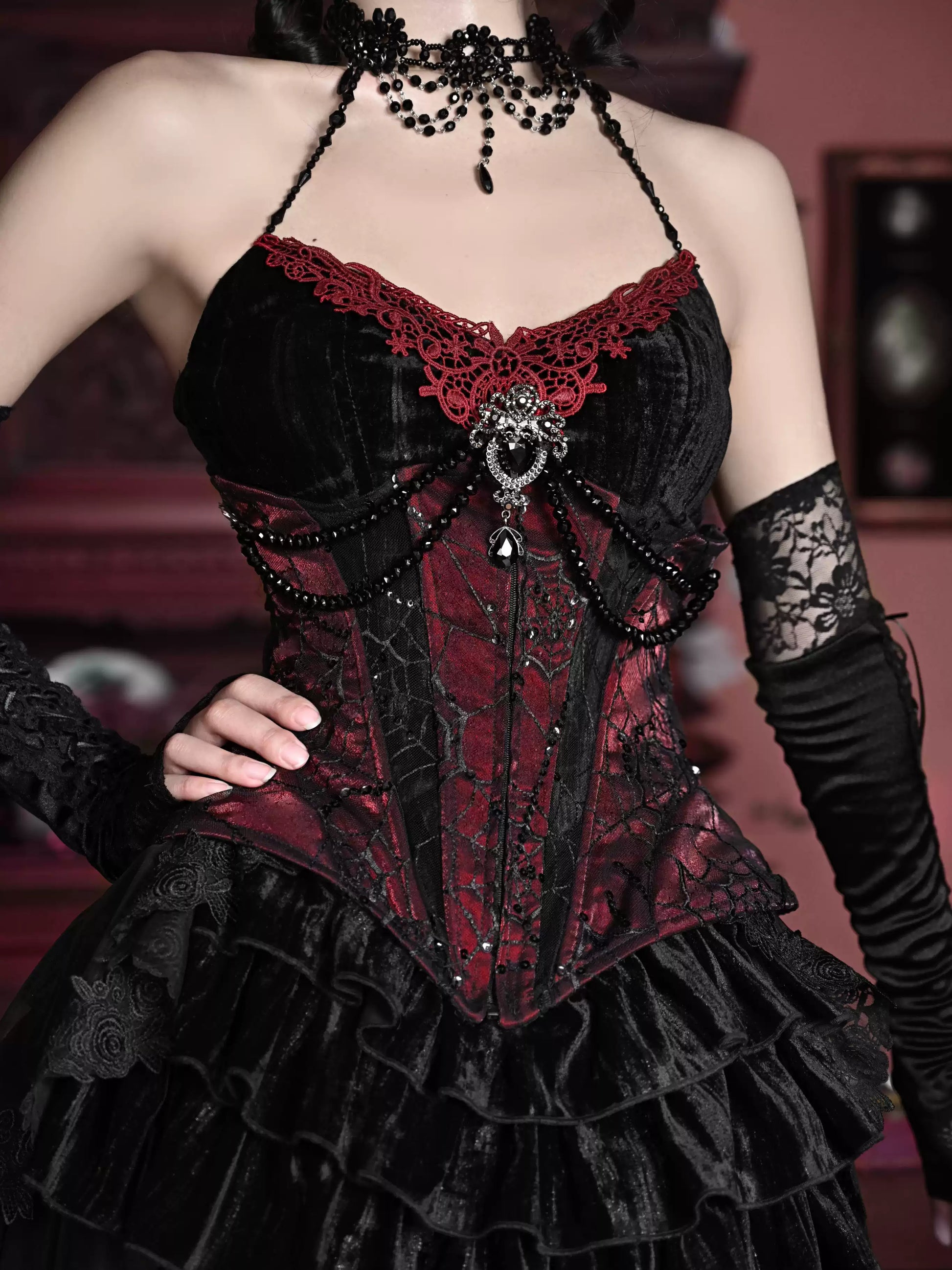 Gothic-style corset with red and black lace details on a blurred background