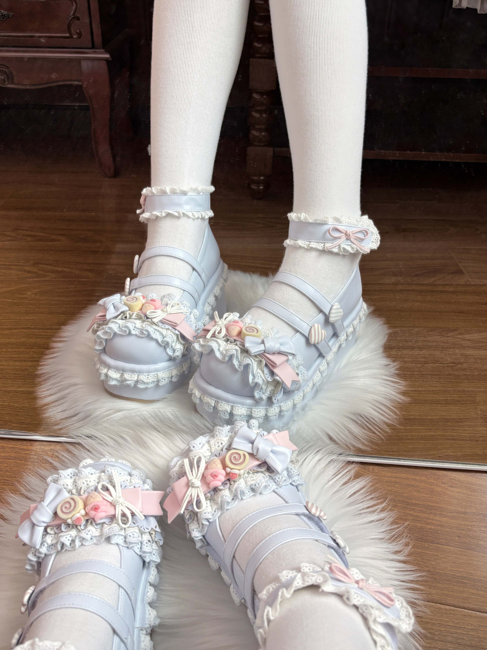 Pastel-colored blue shoes with floral decorations on a wooden floor.