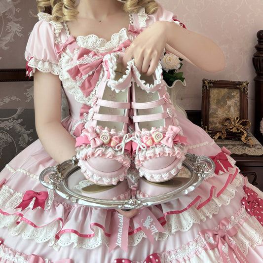 Person in a pink and white dress holding a pink shoe on a silver tray.