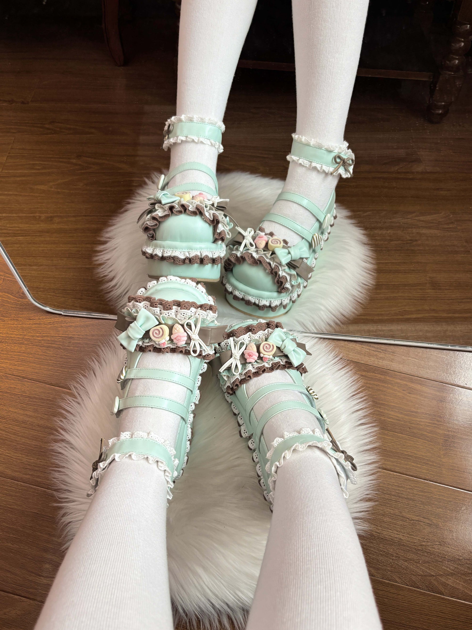 Pastel green sandals with decorative elements on a fluffy white rug.
