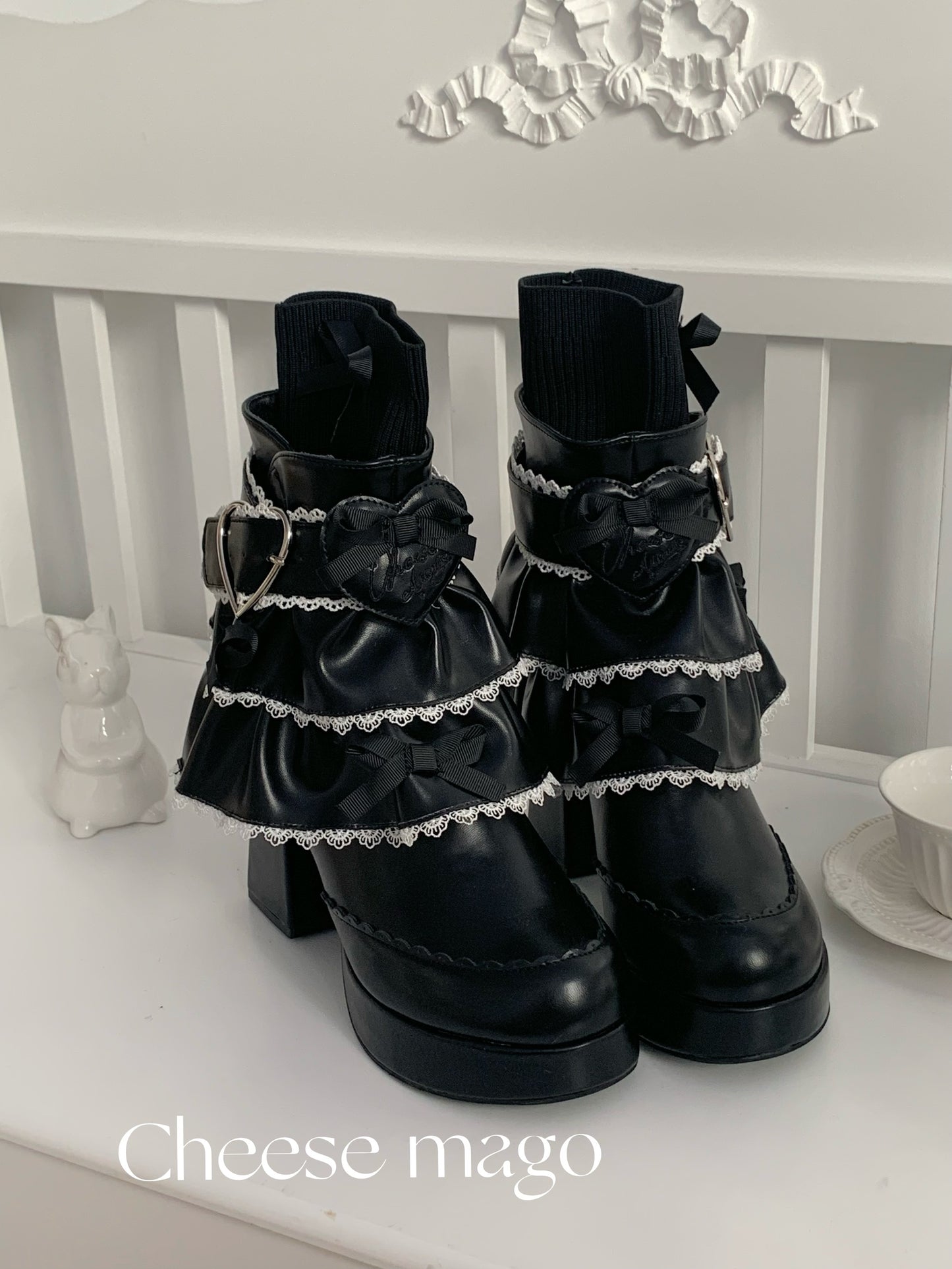 Black lace-up boots with decorative elements on a white surface, branded 'Cheese mago'.