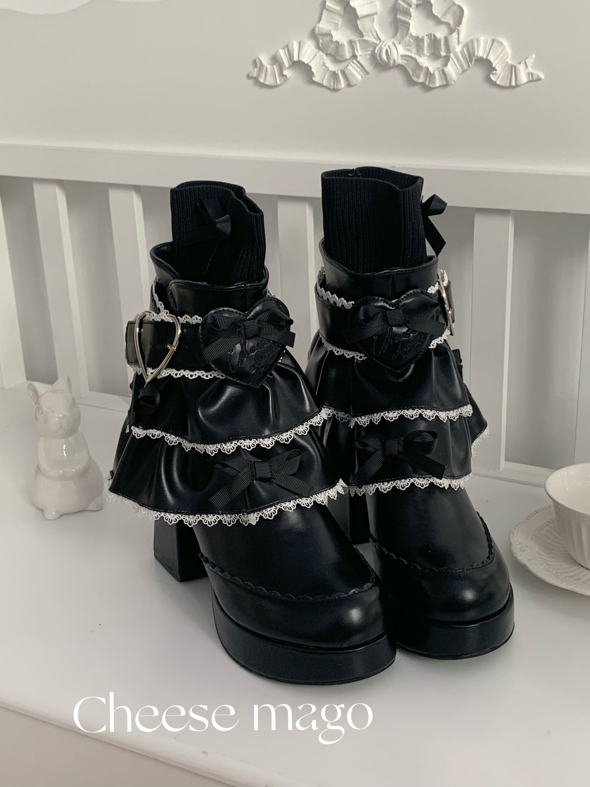 Black lace-up boots with decorative elements on a white surface, branded 'Cheese mago'.