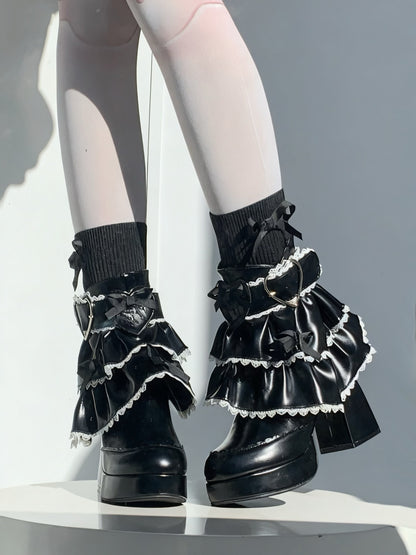 Black ruffled socks with lace details worn with black shoes on a white background