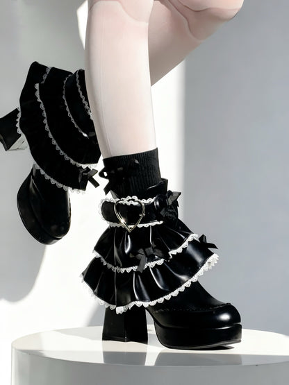 Black ruffled socks with heart details worn by a person on a white background