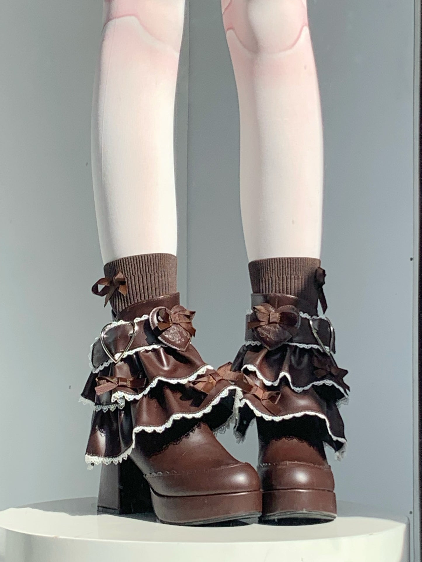 Brown ruffled leg warmers worn with brown shoes on a plain background