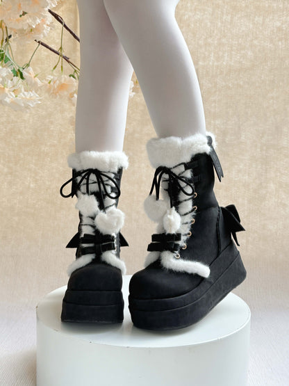 Black platform winter boots with white fur and bows on a neutral background