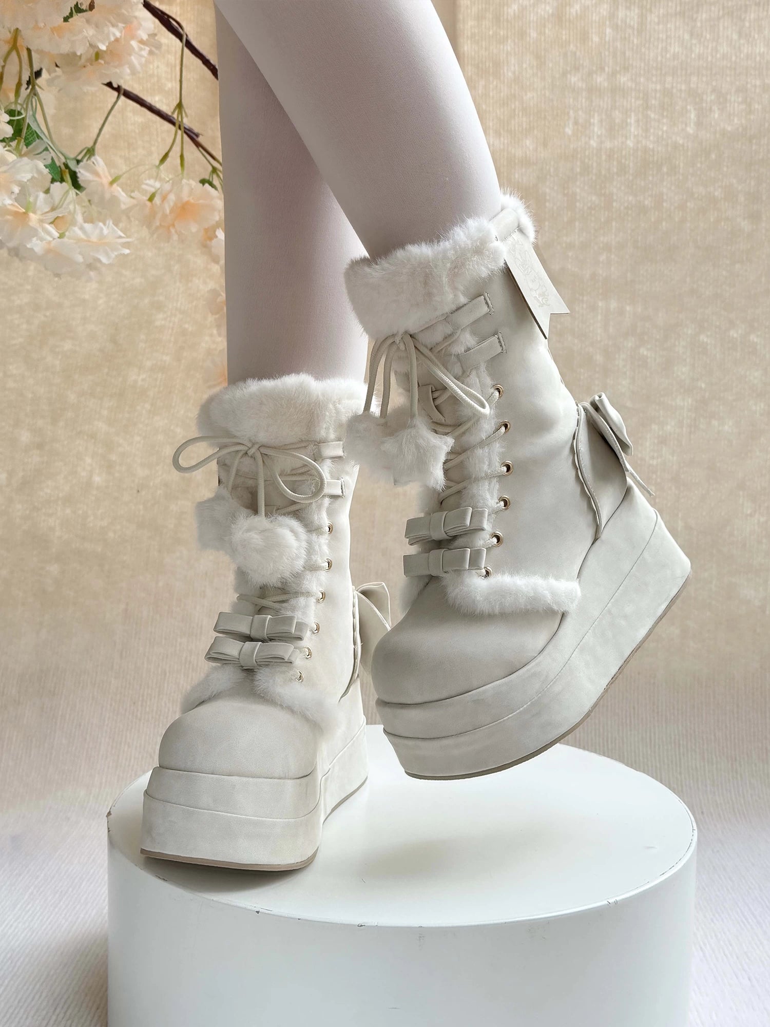 White high-top winter boots with fur trim on a neutral background