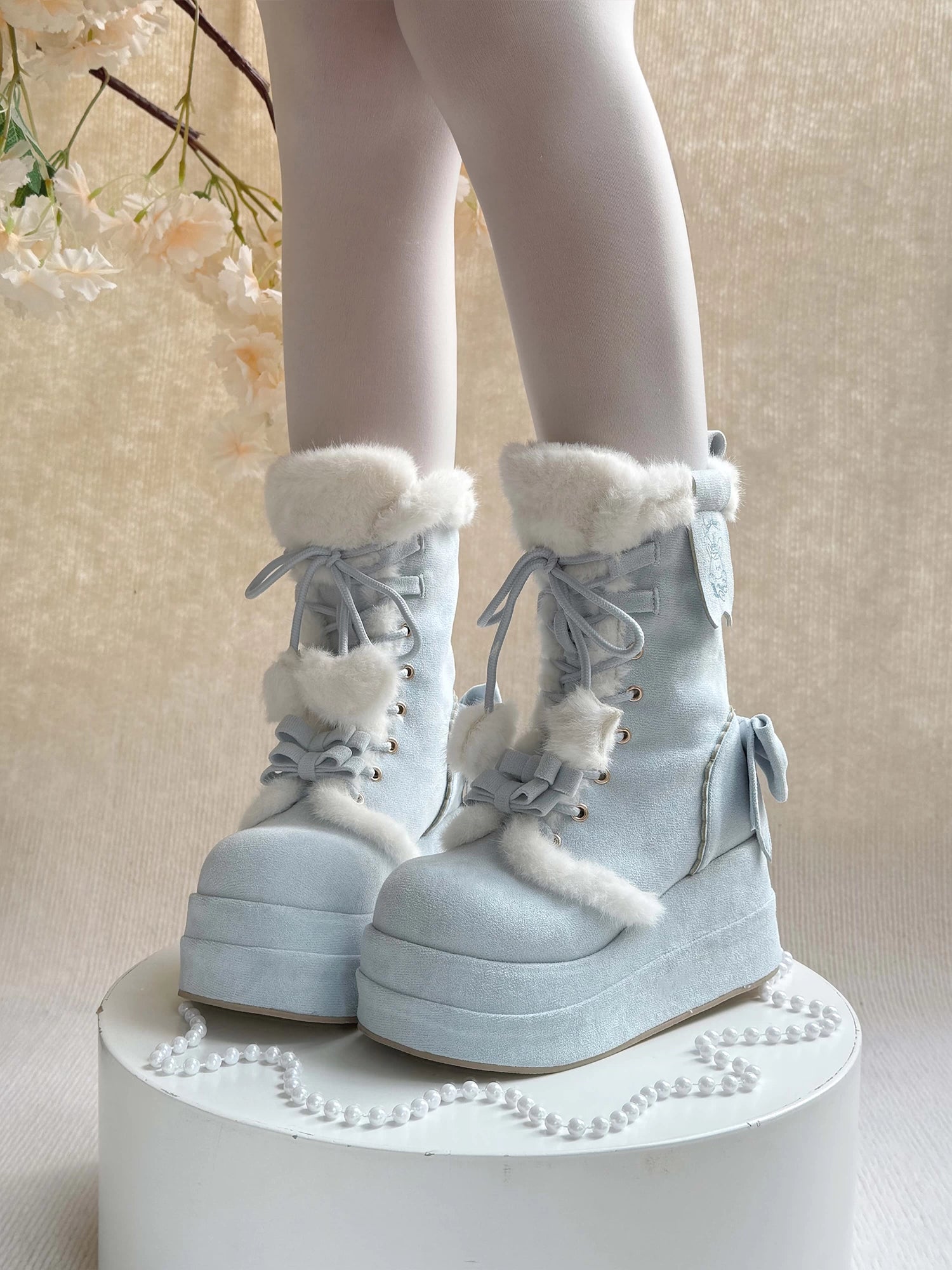 Light blue winter boots with white fur trim on a neutral background