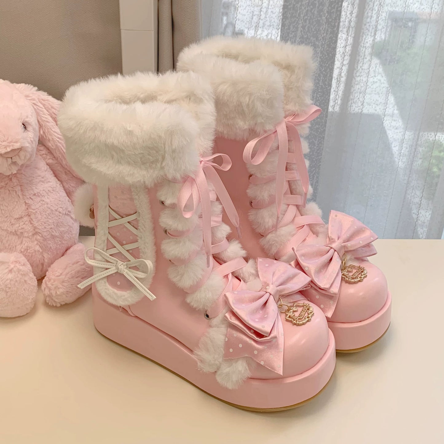 Pink boots with white fur and decorative bows on a light surface.