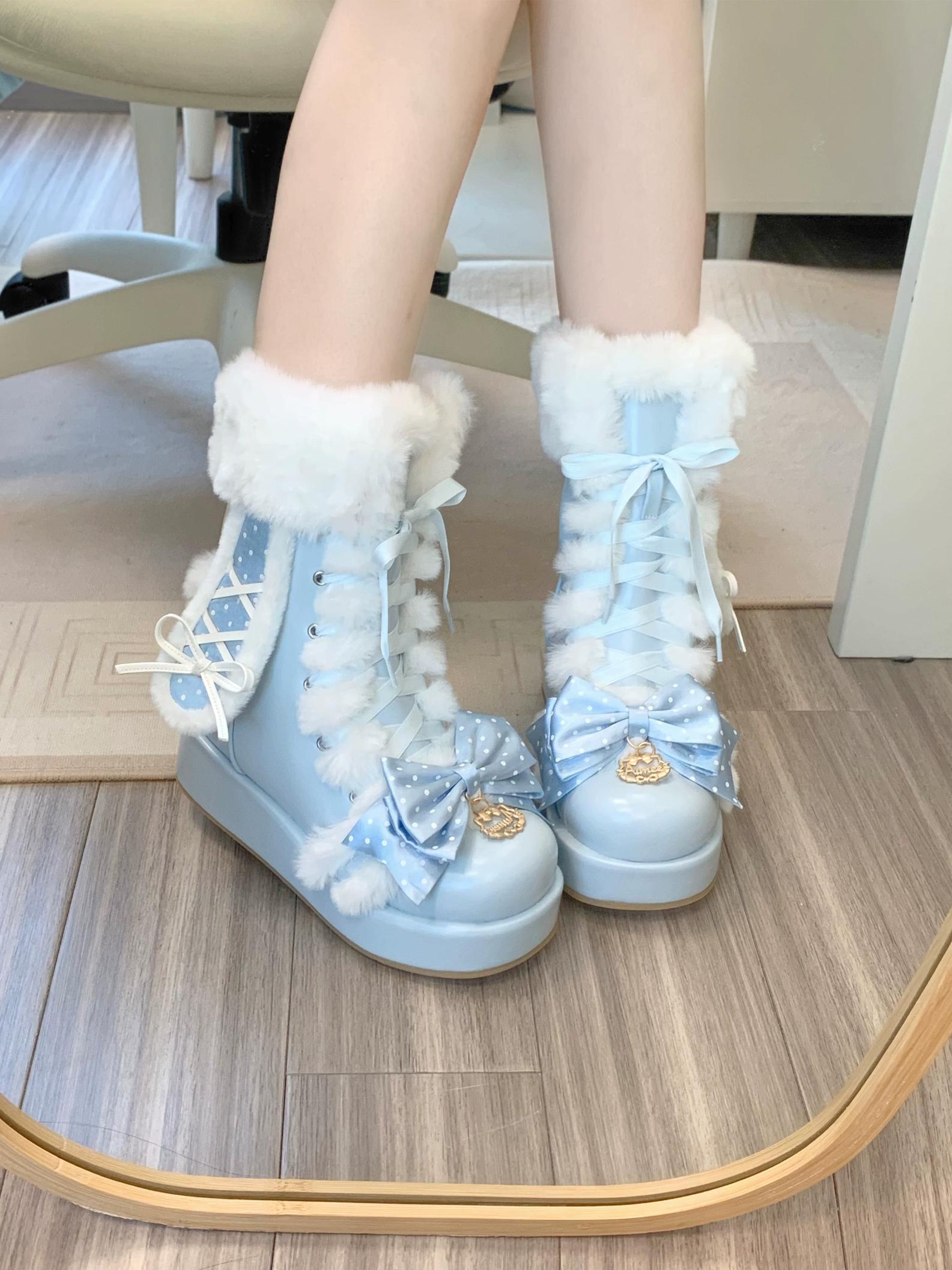 Light blue boots with white fur trim and decorative bows on a wooden floor.