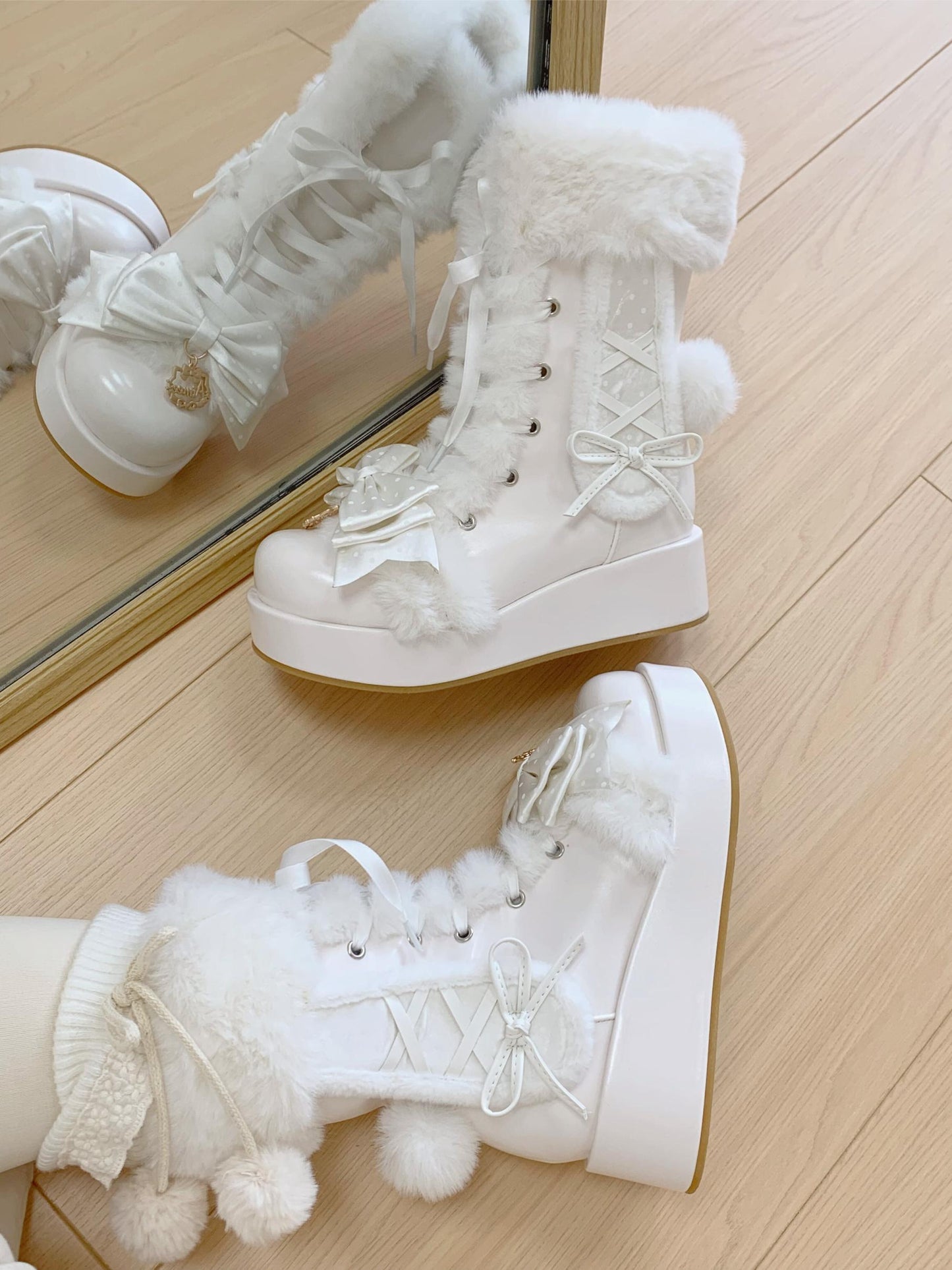 White winter boots with fur trim on a wooden floor