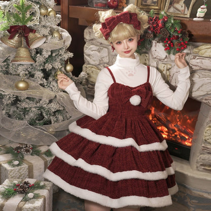 Young girl in a festive red and white dress standing in front of a Christmas tree and fireplace.