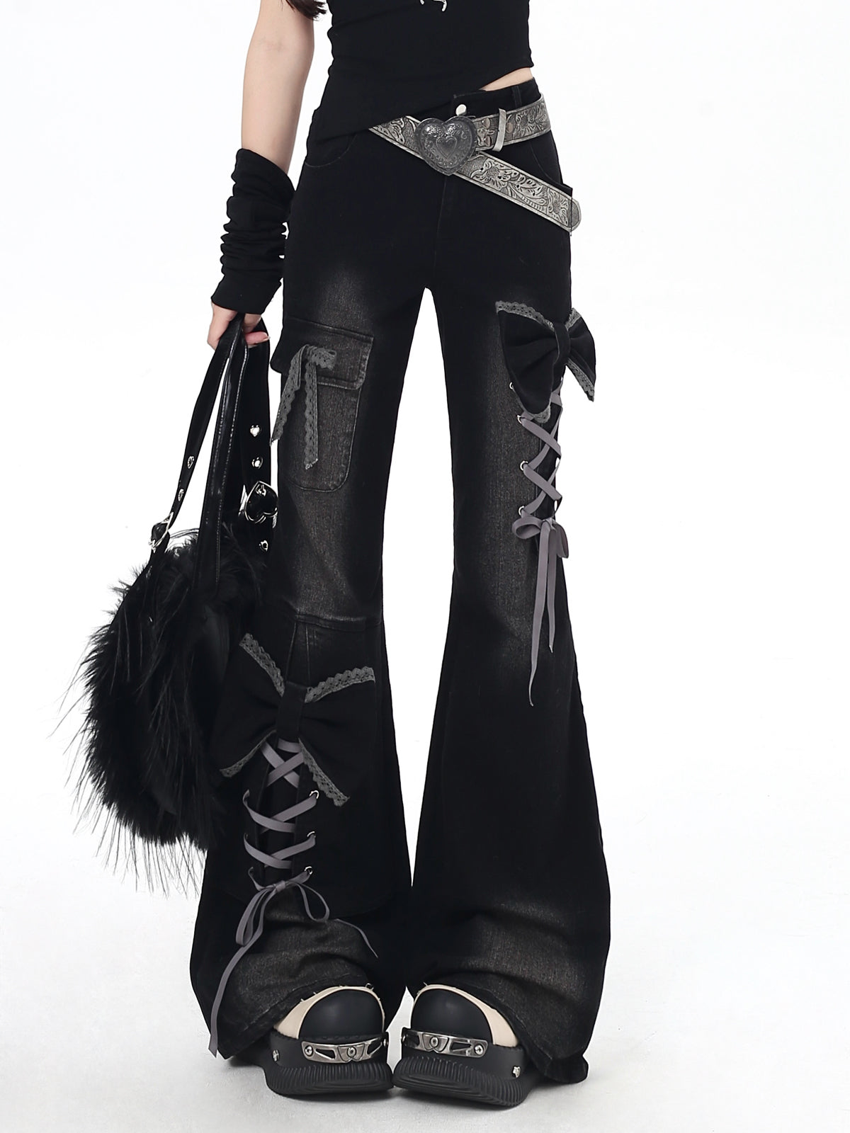 Person wearing black flared pants with lace-up design, black top, and black shoes on a white background.