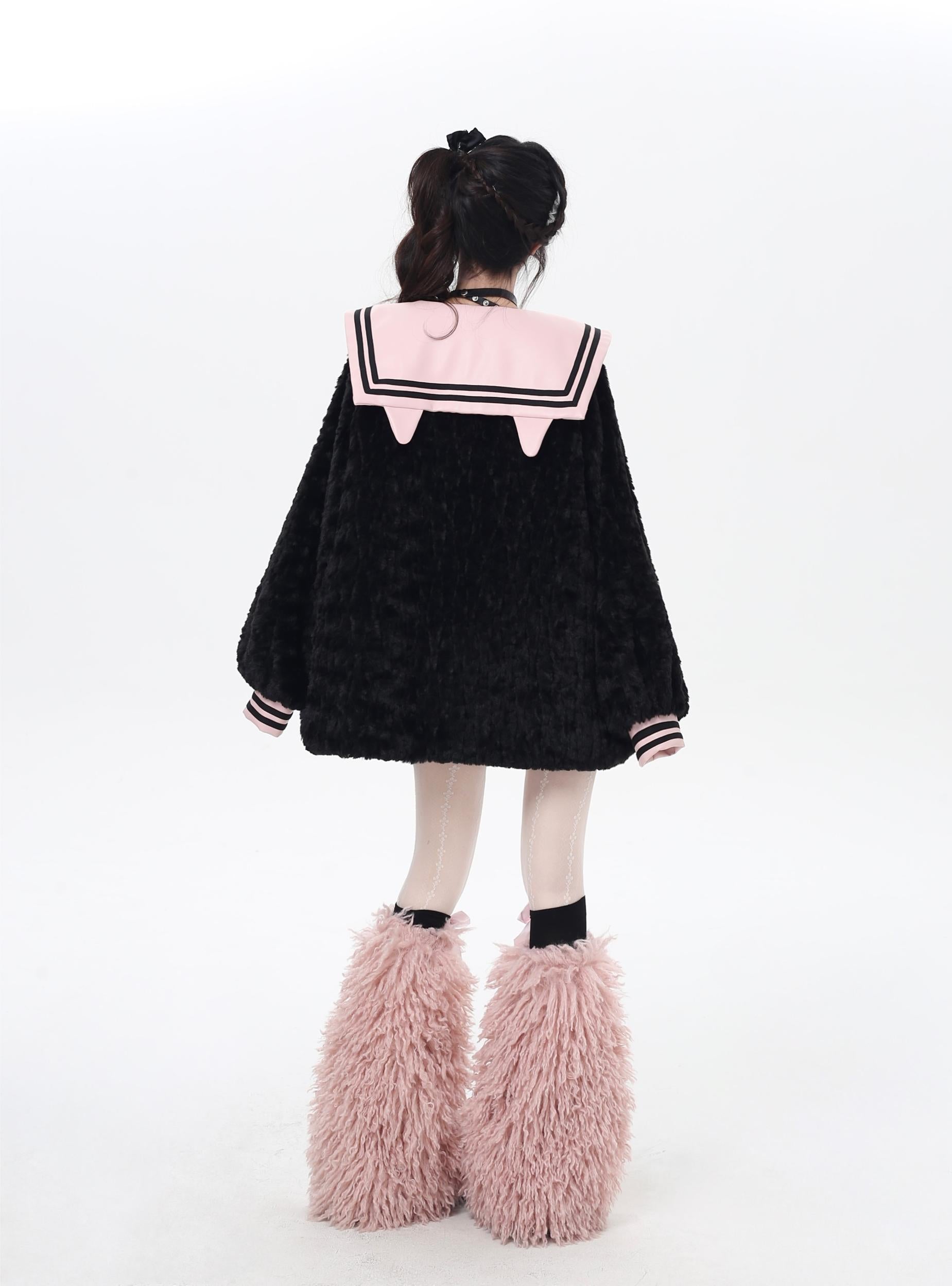 Person wearing a black sweater with pink accents and fluffy pink boots on a white background
